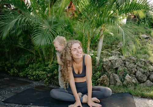 Group of happy children imitating yoga poses outdoors on mats.